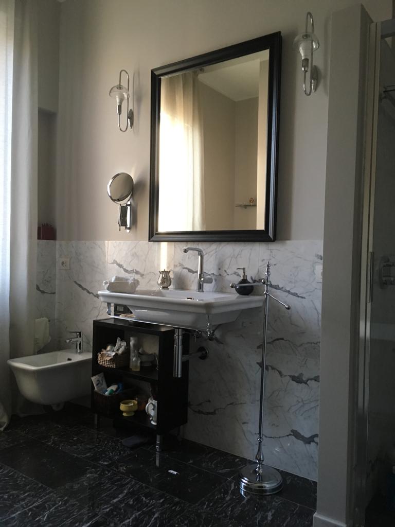 10. Sala da bagno con pavimenti in marmo nero lucidato, illuminazione con applique a parete e sanitari sospesi in ceramica: lavori ultimati.